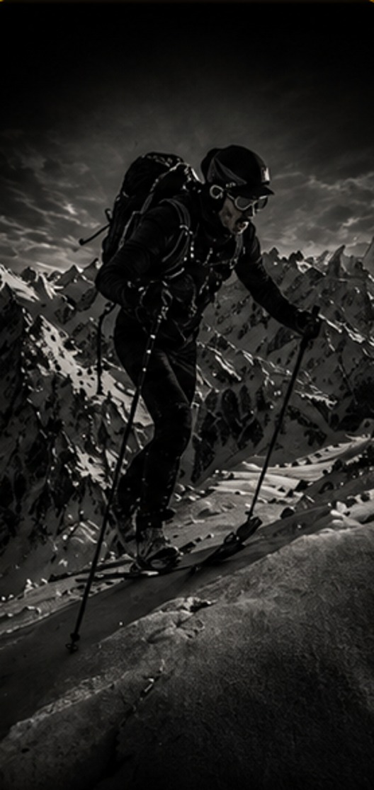 Ski mountaineer skinning up a steep snow slope in the high mountains.